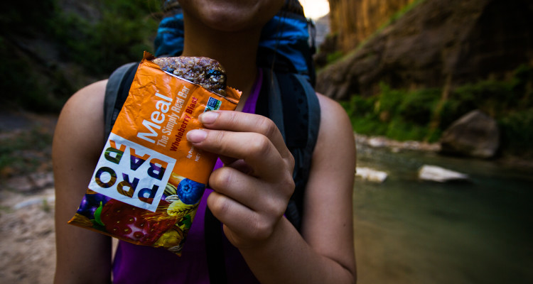 A traveler eats a Probar Meal while backpacking in Zion National Park.