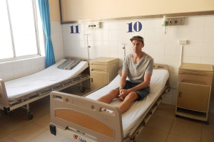 Mark, a tourist, sits in a hospital bed in a hospital in Vietnam.