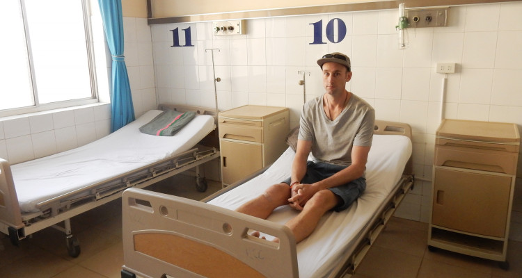 Mark, a tourist, sits in a hospital bed in a hospital in Vietnam.